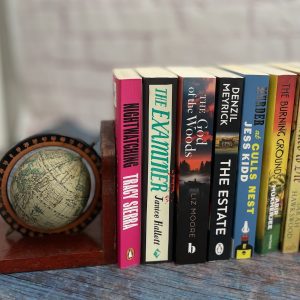 A selection of crime novels with a globe shaped bookend.