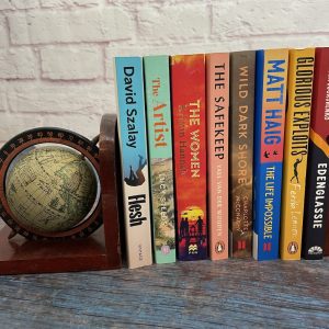 A selecltion of contemporary fiction books with a globe shaped bookend.